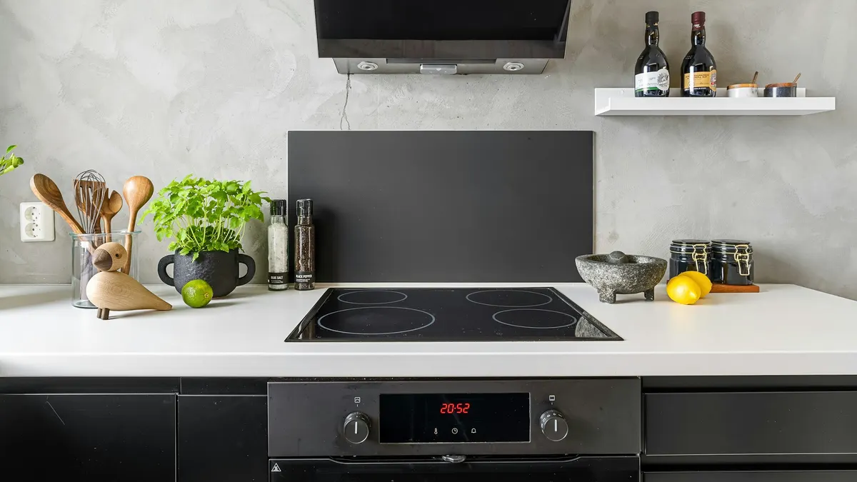 Moderne keuken met een zwarte inductiekookplaat in een wit werkblad en een inbouwoven eronder